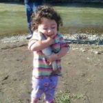 A little girl happily holding a fish, thinking she saved it from drowning.