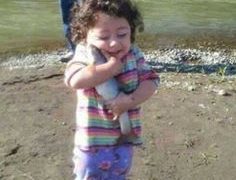 A little girl happily holding a fish, thinking she saved it from drowning.
