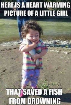 A little girl happily holding a fish, thinking she saved it from drowning.