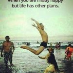 Man jumping at beach while a dog disrupts the fun