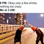 Two people with traffic cones on their heads acting silly at night