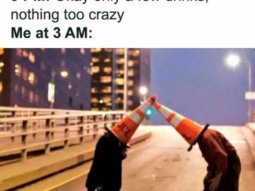 Two people with traffic cones on their heads acting silly at night