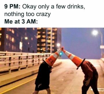 Two people with traffic cones on their heads acting silly at night