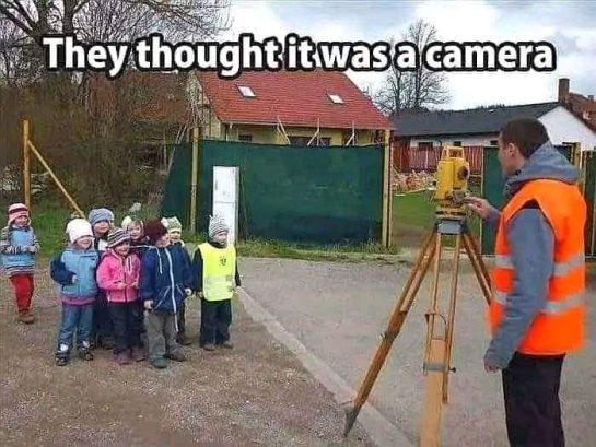Group of kids posing in front of a survey tool thinking it's a camera.
