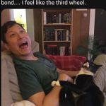 Man and cat bonding on couch, woman feels like third wheel.