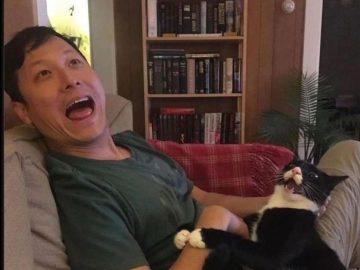 Man and cat bonding on couch, woman feels like third wheel.