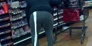 Shopper dragging a long toilet paper trail in a store aisle.