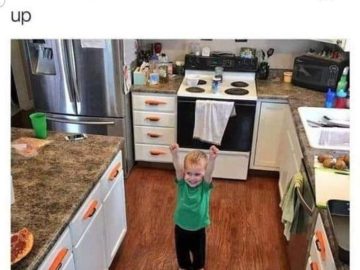 Little boy proudly showing off his organized carrot handles in the kitchen.