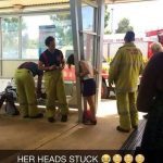 Woman's head stuck in railing with firefighters assisting.