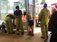 Woman's head stuck in railing with firefighters assisting.