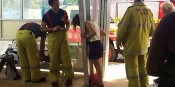 Woman's head stuck in railing with firefighters assisting.