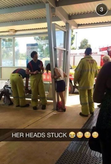 Woman's head stuck in railing with firefighters assisting.