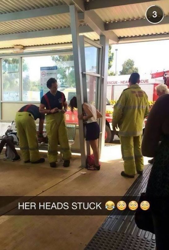 Woman's head stuck in railing with firefighters assisting.