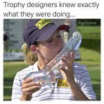 Woman kisses bizarrely shaped golf trophy with a smirk.