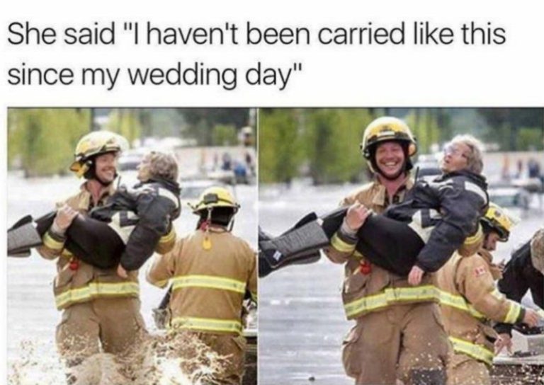 Firefighter carrying a smiling grandma through water, joyful moment.