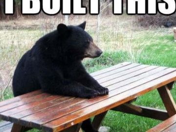 Black bear sitting at picnic table with text "I built this with my bear hands"