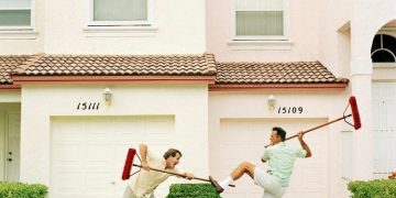 Two neighbors using brooms to keep each other away.