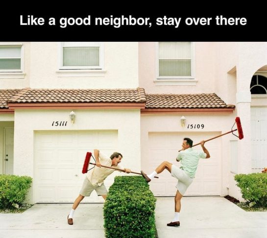 Two neighbors using brooms to keep each other away.