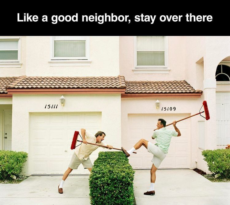Two neighbors using brooms to keep each other away.