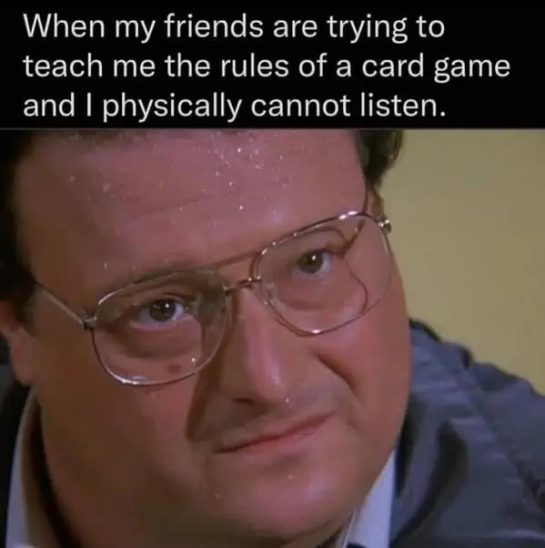 Person sweating as friends teach card game rules, looking confused