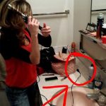 Woman confused with unplugged curling iron in bathroom.