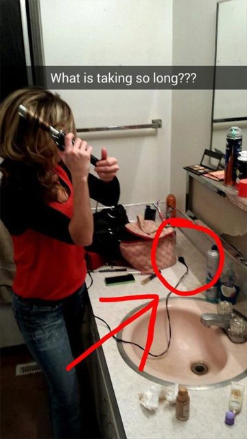 Woman confused with unplugged curling iron in bathroom.