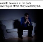 Man sitting in the dark, stressing over electricity bills.