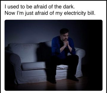 Man sitting in the dark, stressing over electricity bills.