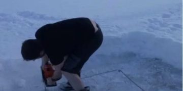 Person cutting a square in ice, about to experience a fail.