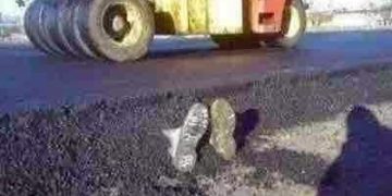 Roller flattens road with boots sticking out in a construction prank.