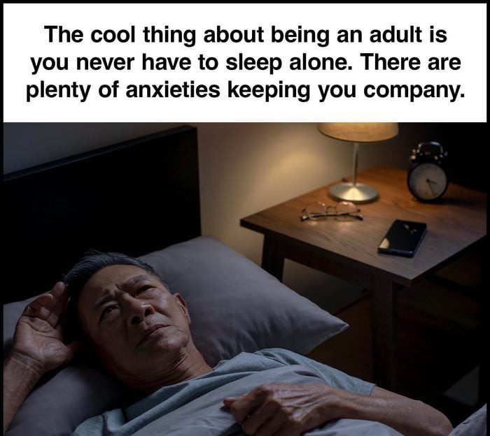 Man lying in bed with open eyes, surrounded by anxieties.