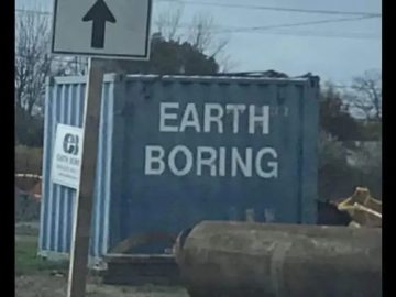 Blue container with "Earth Boring" graffiti under a road sign.