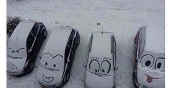 Cars with cartoon faces drawn in snow on their windshields.