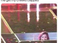 Cat peeking over the bed edge with a cheeky look.