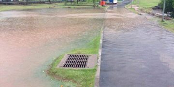 Flooded park path with water bypassing a useless drain.