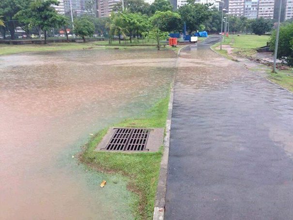 Flooded park path with water bypassing a useless drain.