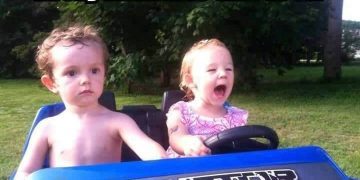 Toddler driving toy car with serious passenger expression