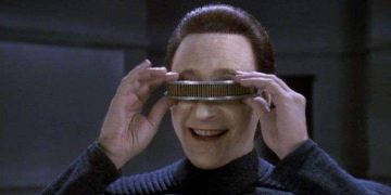 Person tries friend's glasses; humorous vision test moment.