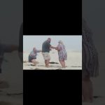 Thumbnail for a funny beach proposal video showing a romantic moment turning into sudden chaos and an awkward fail