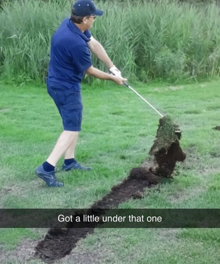 Golfer swings and lifts a giant piece of turf into the air.