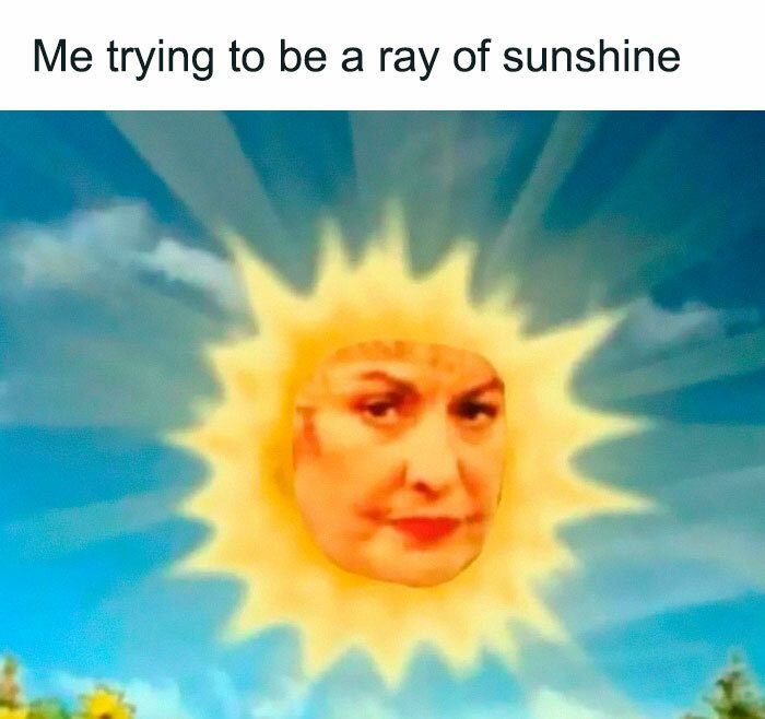 Grumpy sun face in a cheerful sky with "Me trying to be a ray of sunshine."