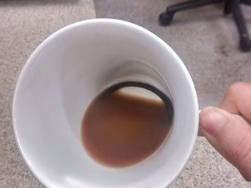 Cat hides hair tie in a coffee cup, surprise revealed.
