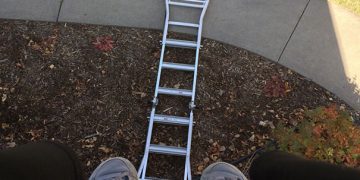 Person stuck on roof with fallen ladder below, shadow visible