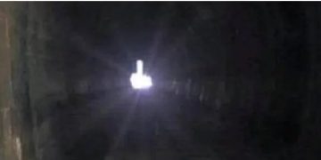 A dark tunnel with a middle finger light at the end.