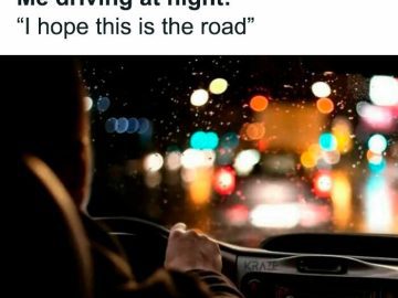 Driver navigating a rainy, blurry road at night with colorful lights.