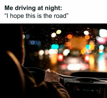 Driver navigating a rainy, blurry road at night with colorful lights.