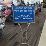 Humorous airport sign prohibiting carpet eating in India.