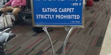 Humorous airport sign prohibiting carpet eating in India.