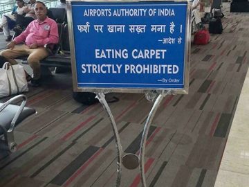 Humorous airport sign prohibiting carpet eating in India.