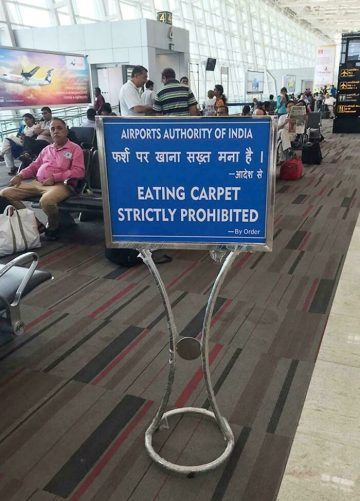 Humorous airport sign prohibiting carpet eating in India.